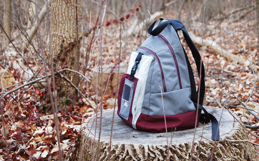 A backpack prototype sits on a stump in the woods