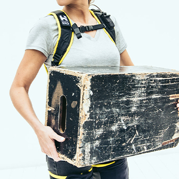 a model wearing the apex exosuit holds a large box