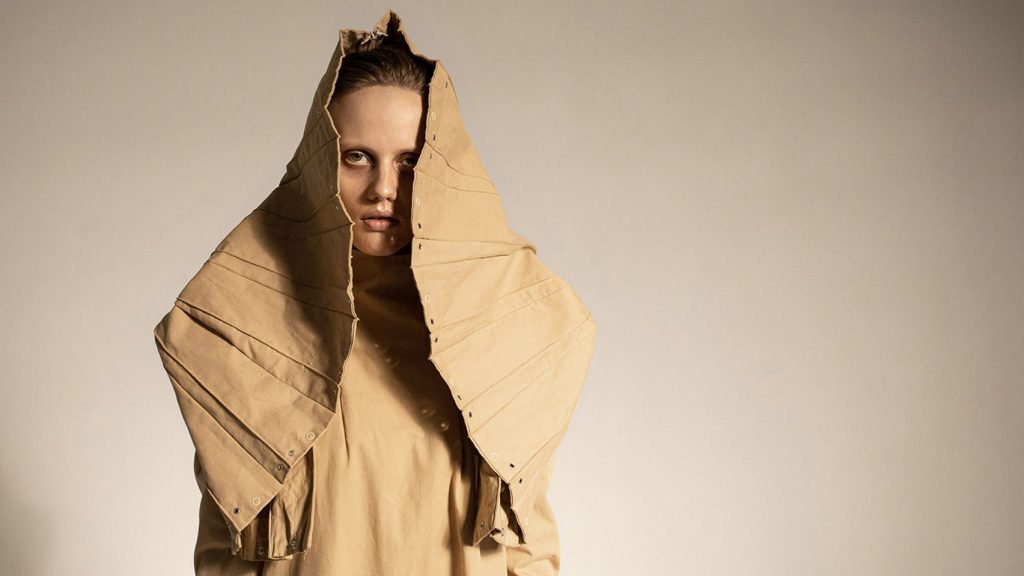 A model wears a tan fashion garment