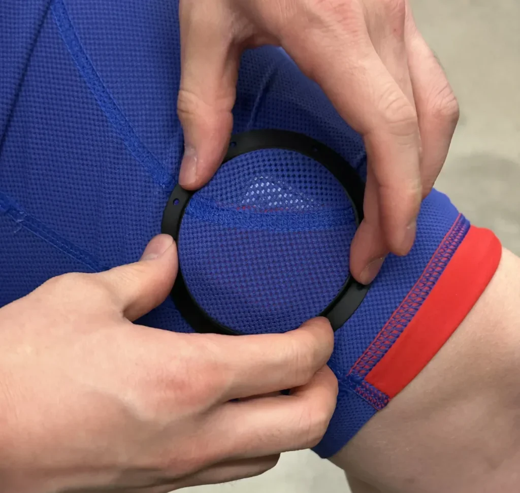 Athlete placing a Moxy Monitor sensor into a custom wearable ring on the thigh