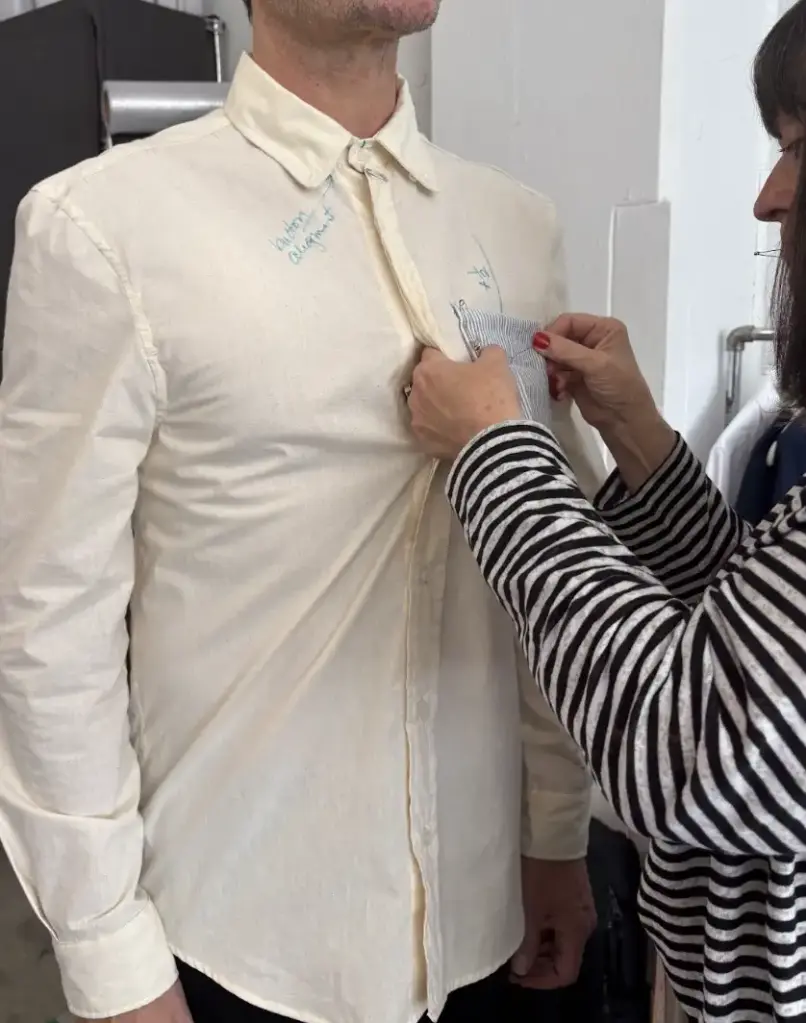 An Interwoven designer adjusting the fit of a cream-colored shirt on a fit model during a SMART ePANTS garment development session