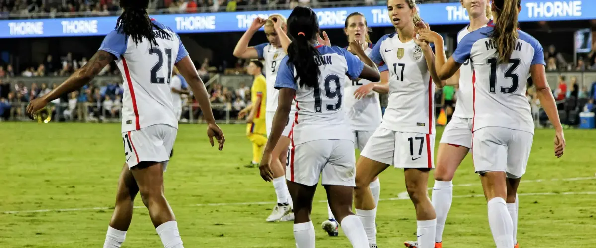 Women's soccer team celebrating together on the field, illustrating how sports uniforms create team unity while supporting athletes with diverse body types.