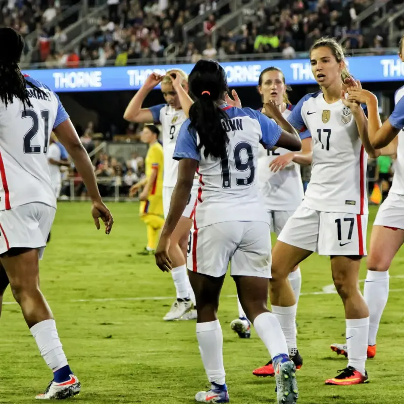 Women's soccer team celebrating together on the field, illustrating how sports uniforms create team unity while supporting athletes with diverse body types.