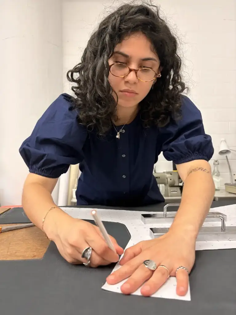 Pratt industrial design intern Chloe Bonnet carefully traces pattern pieces onto technical fabric at a cutting table in the Interwoven studio.