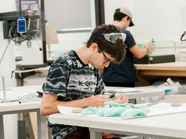 Industrial design student wearing safety goggles working on a project in a design studio workshop at the University of Notre Dame