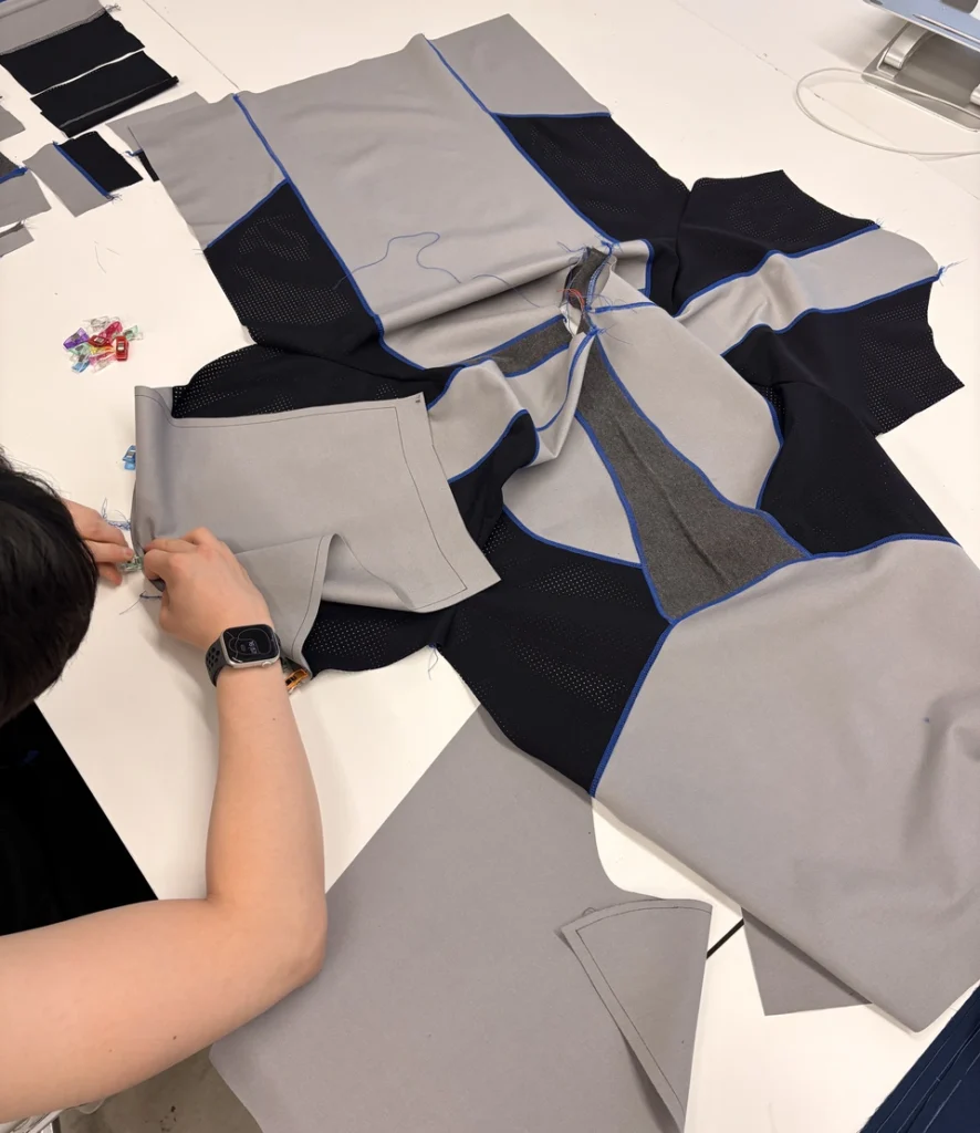 Fabric pattern pieces being assembled into a soft wearable prototype on a worktable.