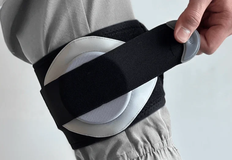 Close-up of a Nevro lower limb wearable with a black adjustable elastic strap and an external power supply holder secured around the leg.
